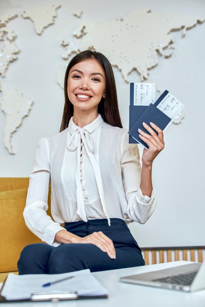 Young woman travel agent holding flight tickets